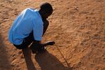 Paris has taught himself to draw. Above, he sketches in the sand at school.