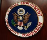 FILE - The emblem of the U.S. Equal Employment Opportunity Commission is shown on a podium in Vail, Colo., Tuesday, Feb. 16, 2016, in Denver.