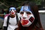 Two people wear masks while attending a protest in Myanmar.