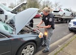 Eugene Community Service Officer Sundi Clark jumpstarts a community member's vehicle at the site of a crash.