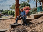 Jimmy sits on a cement wall in Ladera Park while facing away from the camera.