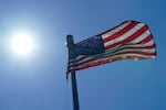 FILE - In this Wednesday, June 30, 2021 file photo, a U.S. flag flies with the sun in the background in downtown Seattle. According to a study released on Wednesday, July 7, 2021, the deadly heat wave that roasted the Pacific Northwest and western Canada “was virtually impossible without human-caused climate change” which also added a few extra degrees to the record-smashing warmth.