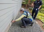 Fire assessment volunteer Reggie Windham looks at the crawlspace vents at the base around a home during an assessment.