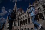 People walk past Hungary's parliament building in Budapest in May.