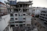 People walk past a destroyed building hit in an Israeli airstrike, in the southern port city of Sidon, Lebanon, Sunday, Nov. 3, 2024.