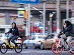 People ride Ofo(L) and Mobike bikeshare in Shanghai.