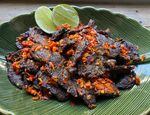 Fried beef with crushed chilis and lime in a green dish.