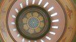 Light enters narrow windows surrounding a floral motif on the ceiling of the Oregon Capitol building.