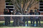 Law enforcement personnel stand outside Robb Elementary School following a shooting on May 24 in Uvalde, Texas. When the gunman arrived at the school, he hopped its fence and easily entered through an unlocked back door, police said.