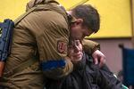 A Ukrainian soldier comforts a woman sitting down.