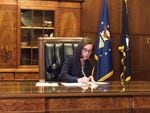 Oregon Gov. Kate Brown signs an executive order in her ceremonial office Thursday.