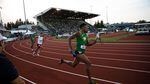 Oregon sprinter Orwin Emilien carries the baton in the 4x400-meter relay. Historic Hayward Field's West Grandstand looms in the background.