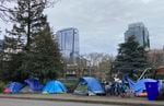 FILE: People camp in tents next to the Interstate 405 freeway in Portland, Ore., on March 31, 2023.
