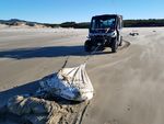 An Oregon State Parks vehicle drags a bag of chia seeds off the beach near Newport, Ore., Tuesday, Dec. 22, 2020.