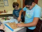 Seventh graders Michael Herrera and Nicolas Barbee cut foam for the model boat's hull.
